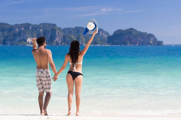 Junge Leute im Sommerurlaub am Strand, Paar hob glückliche Hände am blauen Meer — Stockfoto