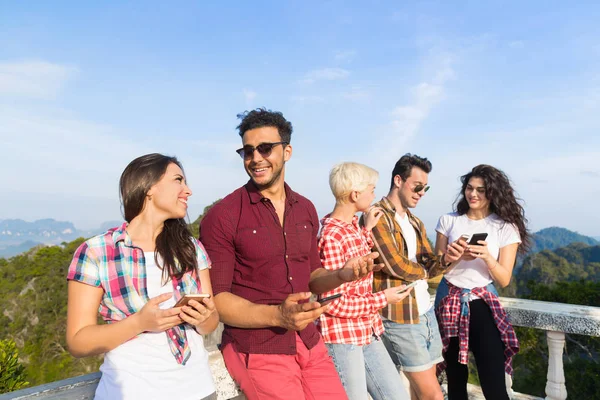 Grupo de jovens na montanha usando celular telefone inteligente conversando on-line amigos asiáticos férias verão — Fotografia de Stock