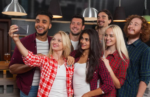 Grupo de jóvenes en el bar, felices amigos sonrientes tomando foto selfie en el pub de cerveza de teléfono inteligente celular —  Fotos de Stock