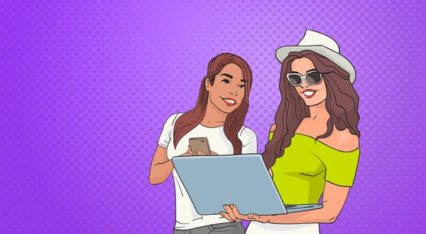 Duas mulheres jovens usando celular telefone inteligente e computador portátil sobre Pop Art colorido estilo retro fundo — Vetor de Stock