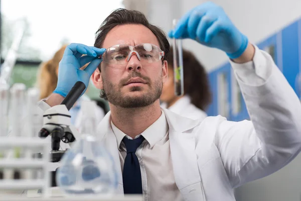 Cientista que analisa a amostra da planta no trabalho do tubo de teste no laboratório da genética — Fotografia de Stock