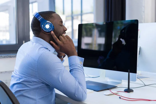 Hombre de negocios afroamericano escucha música con auriculares en el espacio de coworking moderno, hombre de negocios adulto relajándose en el freno —  Fotos de Stock