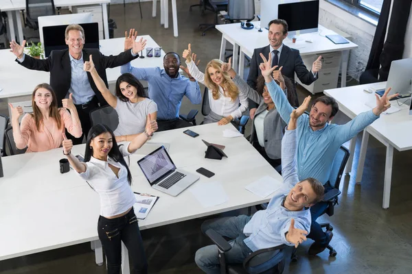 Éxito Emocionado Mix Race Empresarios Equipo Sentado en la mesa en la reunión, sosteniendo la mano levantada Feliz sonriente hombre y mujer de negocios — Foto de Stock