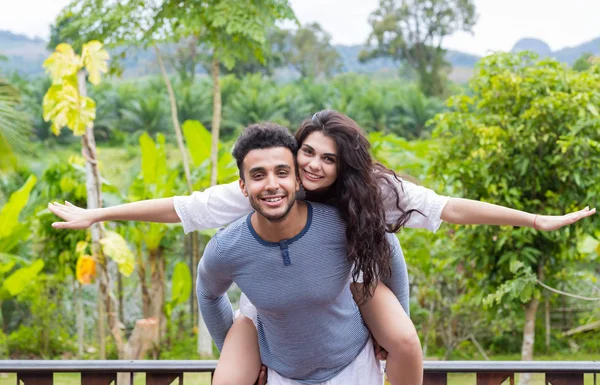 Happy Latin Man Carry Woman On Back, Young Couple Over Green Tropical Rain Forest Landscape