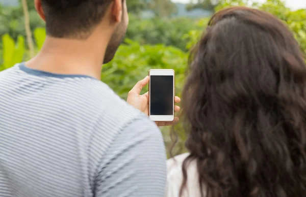 Homem e mulher seguram o telefone esperto da pilha com tela vazia, vista traseira traseira sobre a paisagem tropical da floresta — Fotografia de Stock