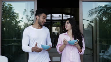 Çift erkek ve kadın tabak yulaf ezmesi ile açık havada tutan Kahvaltı, mutlu yaz terasında yürürken konuşmak