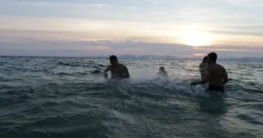 Gün batımı, neşeli insanlar genç Yüzme sahilde birlikte yaz tatili sırasında denizde sıçramasına arkadaş grubu