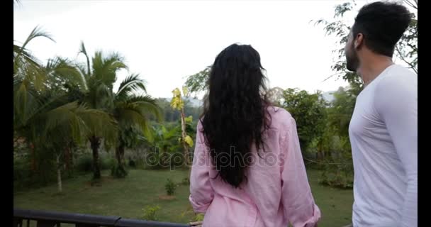 Vista trasera de la joven pareja de pie en la terraza de verano disfrutando del paisaje de bosque tropical mezcla raza hombre y mujer al aire libre en la mañana — Vídeos de Stock