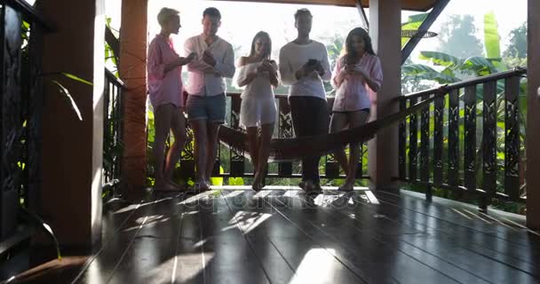 Messages de groupe avec téléphones intelligents cellulaires sur la terrasse d'été, amis bavardant en ligne en plein air le matin 