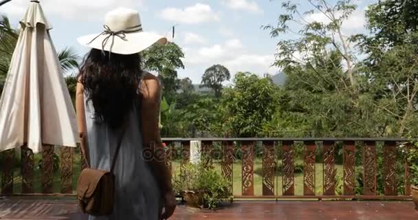 Donna che cammina sulla terrazza estiva Vista posteriore della giovane ragazza guardando il bellissimo paesaggio tropicale dal balcone dell'hotel — Video Stock
