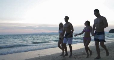 Bir grup insan yürüyen At Sunset Beach, yaz tatili sırasında iki Mix yarış çift iletişim