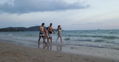 Mix yarış insanlar yürüyüş On Beach, neşeli genç erkekler ve kadınlar iletişim üzerine yaz, sahil grup