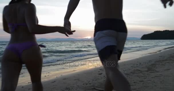 Young Couple Run In Sea Holding Hands Back Rear View Happy Man And Woman Tourists On Beach At Sunset — Stock Video