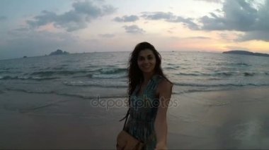 Mutlu kadın ve adam günbatımı hareket kamera noktası deniz kıyısı üzerinde genç çiftin görünümünün kumsalda yürürken elele