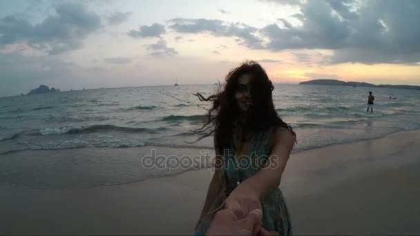 Joven mujer caminando en playa sosteniendo la mano del hombre al atardecer acción cámara punto de vista de feliz sonrisa chica en la playa — Vídeos de Stock