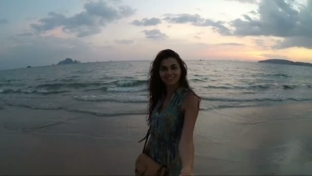 海岸で若いカップルのビューのサンセット アクション カメラ ポイントのビーチを歩いて手を取り合って幸せな男女 — ストック動画
