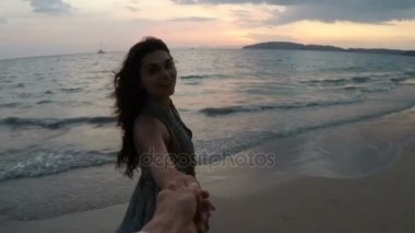 Mutlu kadın ve adam günbatımı hareket kamera noktası deniz kıyısı üzerinde genç çiftin görünümünün kumsalda yürürken elele