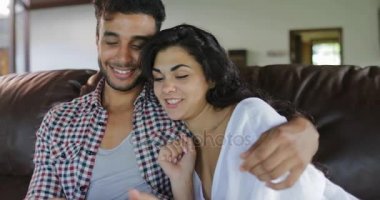 Oturma odası, genç adam ve kadın Online Modern Daire iç tarama konuşurken Tablet bilgisayar kullanarak Koç oturan çift kucaklama