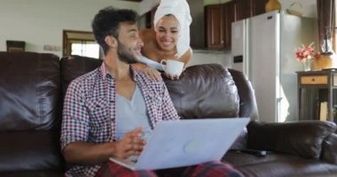 Kadın konuşmak Online oturma odasında Modern Daire iç konuşmaya sabah genç çift tarama dizüstü bilgisayar kullanan Koç üzerinde oturan adam için