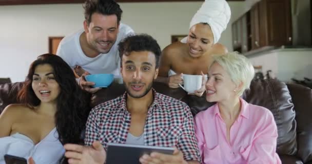 Mladí lidé, skupina ráno Watch Tv Sit na trenéra v moderní apartmán mluví použití tabletového počítače — Stock video