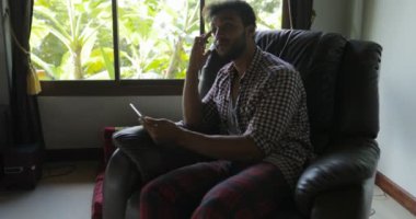 Genç adam işadamı Mix yarış fotoğrafçı gülümseyen dijital aygıt kullanarak yeni fikir evde, koltukta oturan çizim Tablet bilgisayar ile çalışma