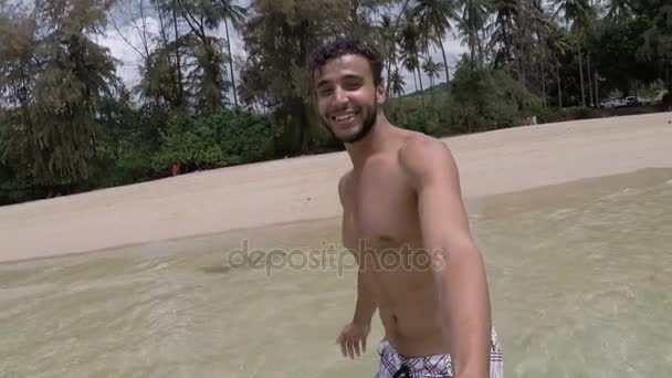 Красавчик латиноамериканец гуляет по пляжу, держа за руку, говорящую экшн камеру POV молодой пары на берегу моря — стоковое видео
