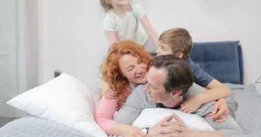 Mutlu gülümseyen aile yatak odası birlikte yatakta sabah yatarken eğleniyor
