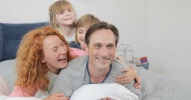 Aile babası yatak odasında, neşeli sabah çocuklar ebeveynleriyle birlikte yalan gülümseyen mutlu
