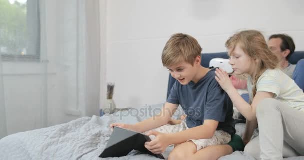 Los niños que usan la tableta mientras la madre usa gafas de realidad virtual en el dormitorio, la familia juntos se divierten en casa — Vídeos de Stock