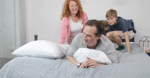 Glückliche Familie im Schlafzimmer Kinder und Eltern Kommunikation liegend zusammen auf Vater auf dem Bett am Morgen — Stockvideo