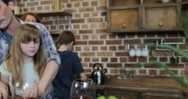 Mutfakta, mutlu anne baba evde gıda hazırlama iki çocukla bakarak yemek ile veliler yardım çıkarmaya söz