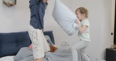 Mutlu çocuklar eğleniyor ebeveyn yatak odası yastıklar mücadele sabah anne iken ve yalancı Pn gülüyor yatak baba