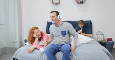 Mutlu aile birlikte sabah yatak harcama zamanında müzik yeni kulaklık kullanarak