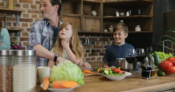 Família feliz na cozinha preparando alimentos, mãe olhando para o pai e filhos cozinhando juntos em casa — Vídeo de Stock