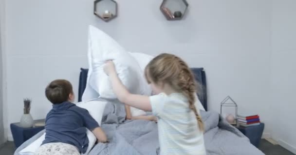 Děti s polštáři bojovat na rodiče posteli, šťastné rodinné zábavy v ložnici