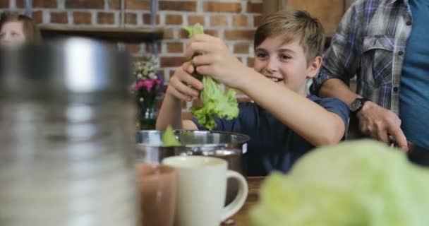 Padre e hijo cocinando ensalada juntos en la cocina picando verduras, familia feliz preparando comida juntos — Vídeos de Stock