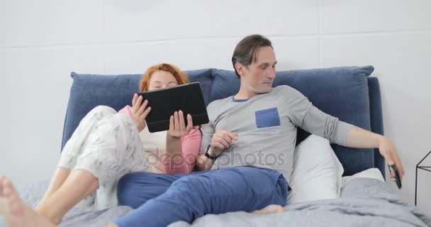 Coupe acostado en la cama usando la computadora digital de la tableta, hombre y mujer que hablan en Internet de la exploración del dormitorio — Vídeos de Stock