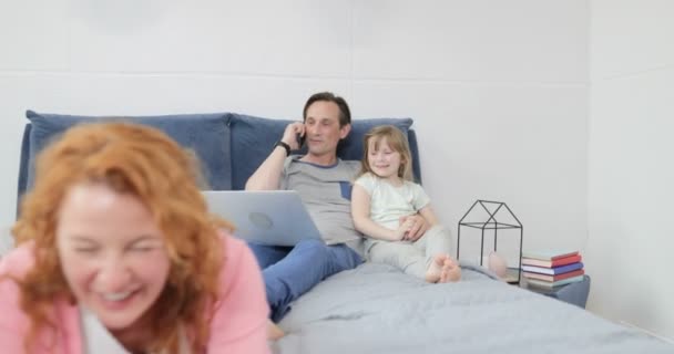 Familia feliz juntos en el dormitorio madre e hijo usando la computadora de la tableta sobre abrazar padre e hija — Vídeos de Stock