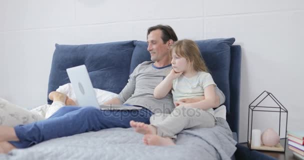 Семья с помощью планшета и ноутбука компьютер в спальне счастливые родители проводят время с детьми дома — стоковое видео