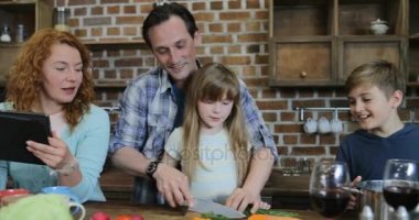 Mutlu aile mutfak pişirme, baba ve kızı dijital Tablet ile Internet içinde iken annesi tarama tarifi Sebze Doğrama