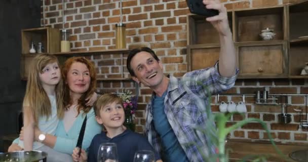 Ευτυχισμένη οικογένεια λήψη Selfie φωτογραφία, ενώ το μαγείρεμα στην κουζίνα τους γονείς και τα παιδιά στο σπίτι προετοιμασία τροφίμων — Αρχείο Βίντεο