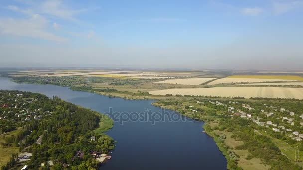 Vista aérea do rio azul com vila pequena e campos em bancos, tiro do drone da paisagem rural do verão — Vídeo de Stock