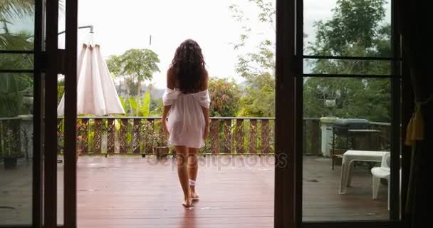 Tjej gå ut till terrassen sträcker armarna tillbaka bakifrån, morgon utsikt över Tropic skog — Stockvideo