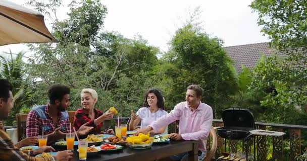 Mensen die voedsel eten op terras jonge vrienden praten zittend aan tafel buiten communicatie — Stockvideo