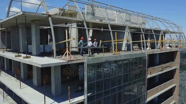 Vista aérea do canteiro de obras e grupo de construtores trabalhando juntos, equipe de engenheiros na construção — Vídeo de Stock