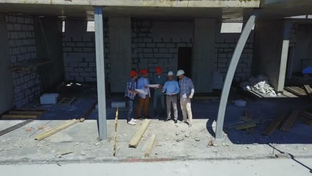 Colpo aereo di squadra costruttori in cantiere discutendo piano di progetto con architetto e contraente utilizzando il progetto — Video Stock