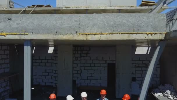 Plano aéreo del equipo de constructores en el sitio de construcción discutiendo el plan del proyecto con el arquitecto y el contratista usando el proyecto — Vídeos de Stock