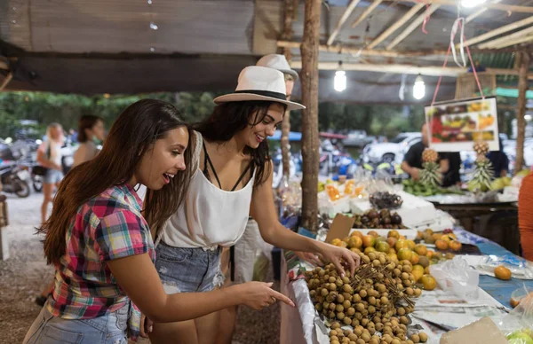 Due donne che scelgono frutta esotiche sul mercato di strada tropicale giovani turisti femminili sul bazar asiatico — Foto Stock