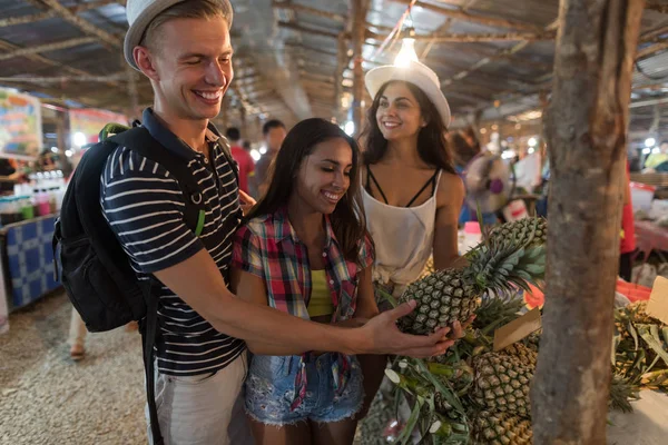 Group Of Tourists Choosing Pineapple On Tropical Street Market In Thailand Young People Buying Fresh Fruits