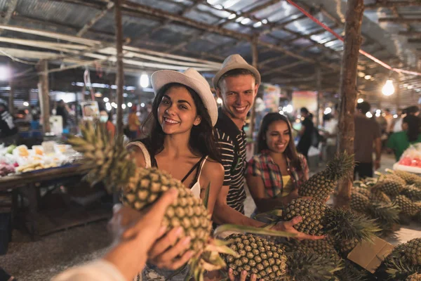 Csoport a turisták vásárlási ananász a trópusi utcai piac, a fiatalok Thaiföld vásárlás friss gyümölcsök — Stock Fotó